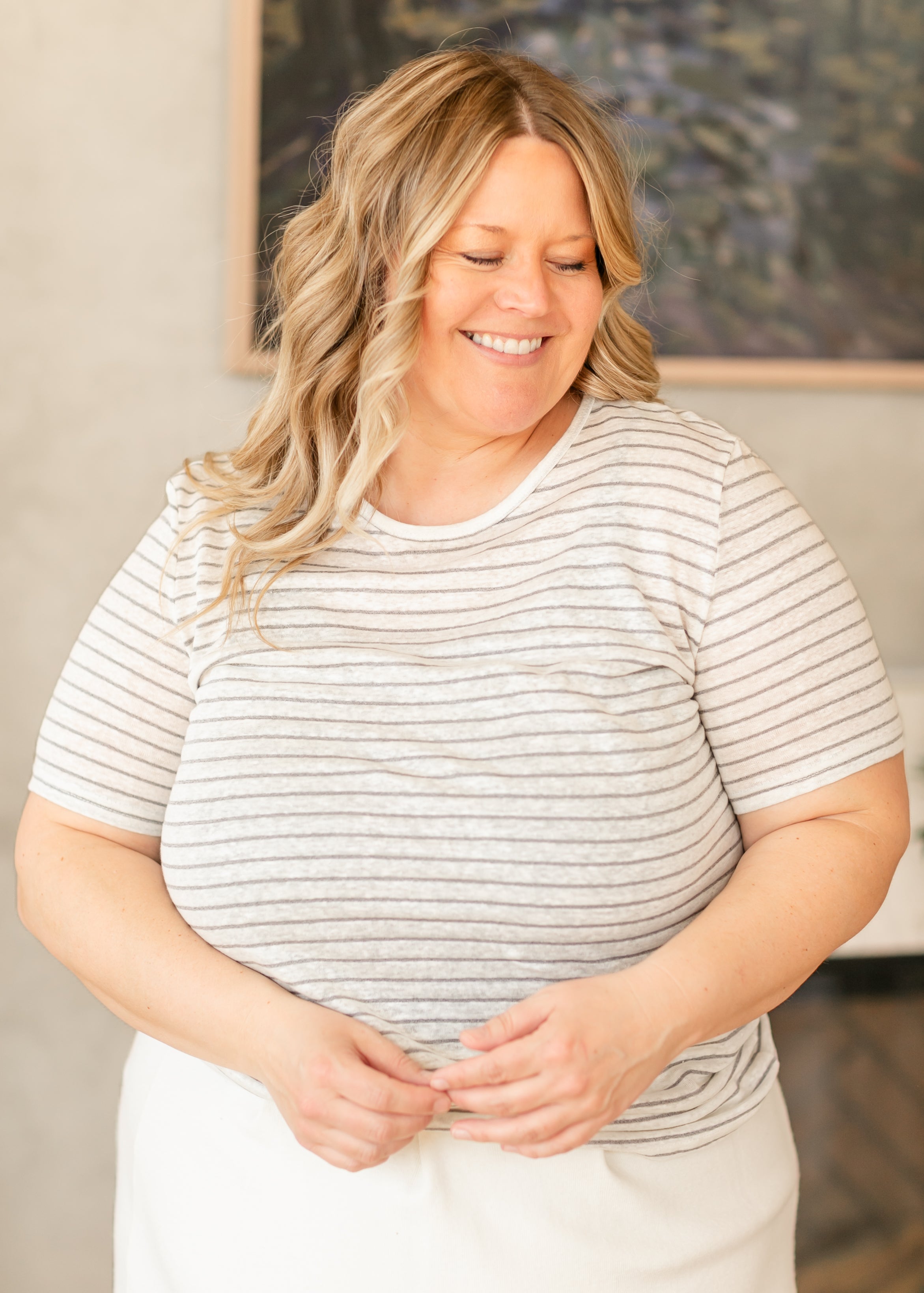 Woman wearing a striped shirt standing indoors with a neutral background