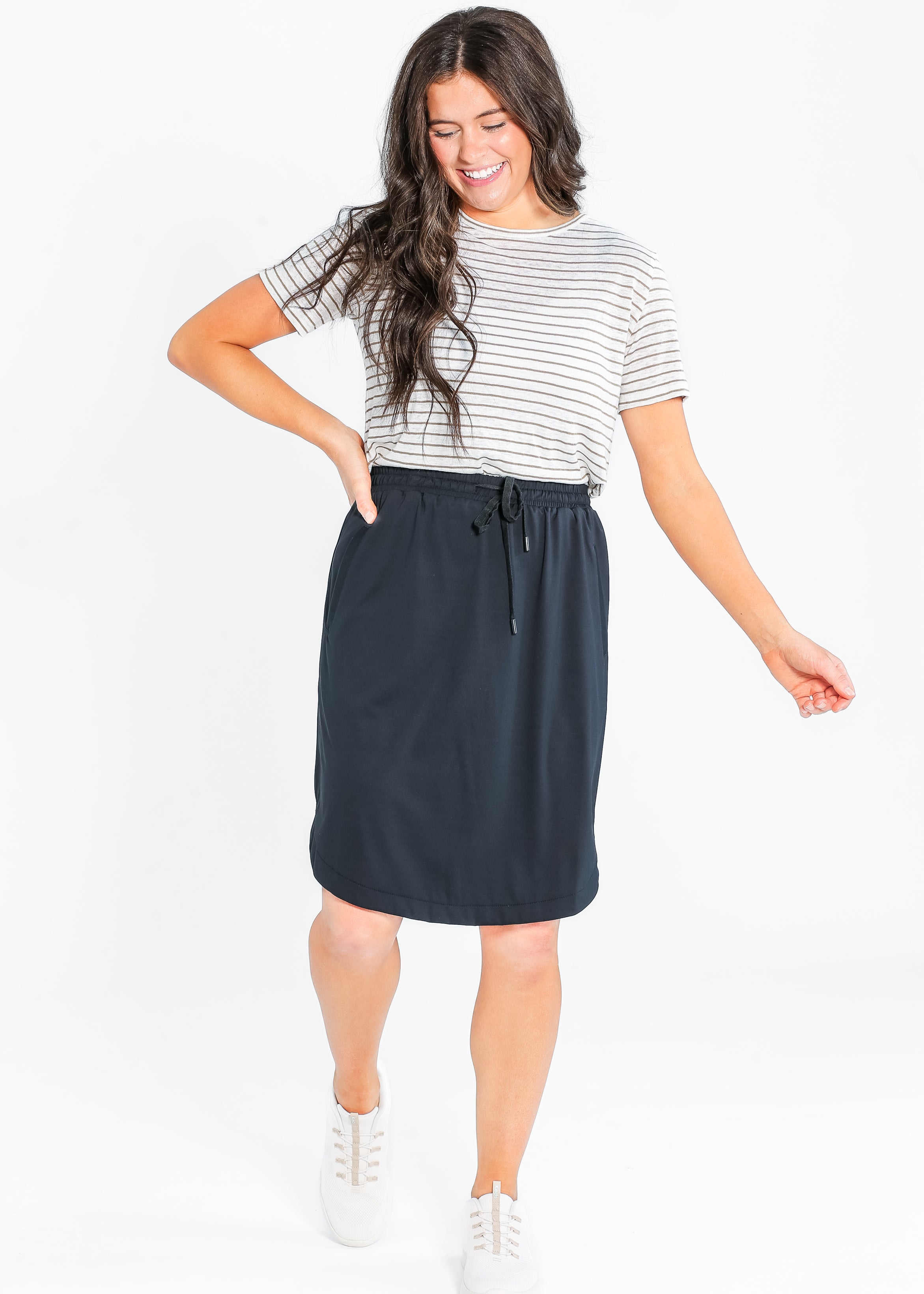 Woman wearing a striped shirt and navy skirt on a white background