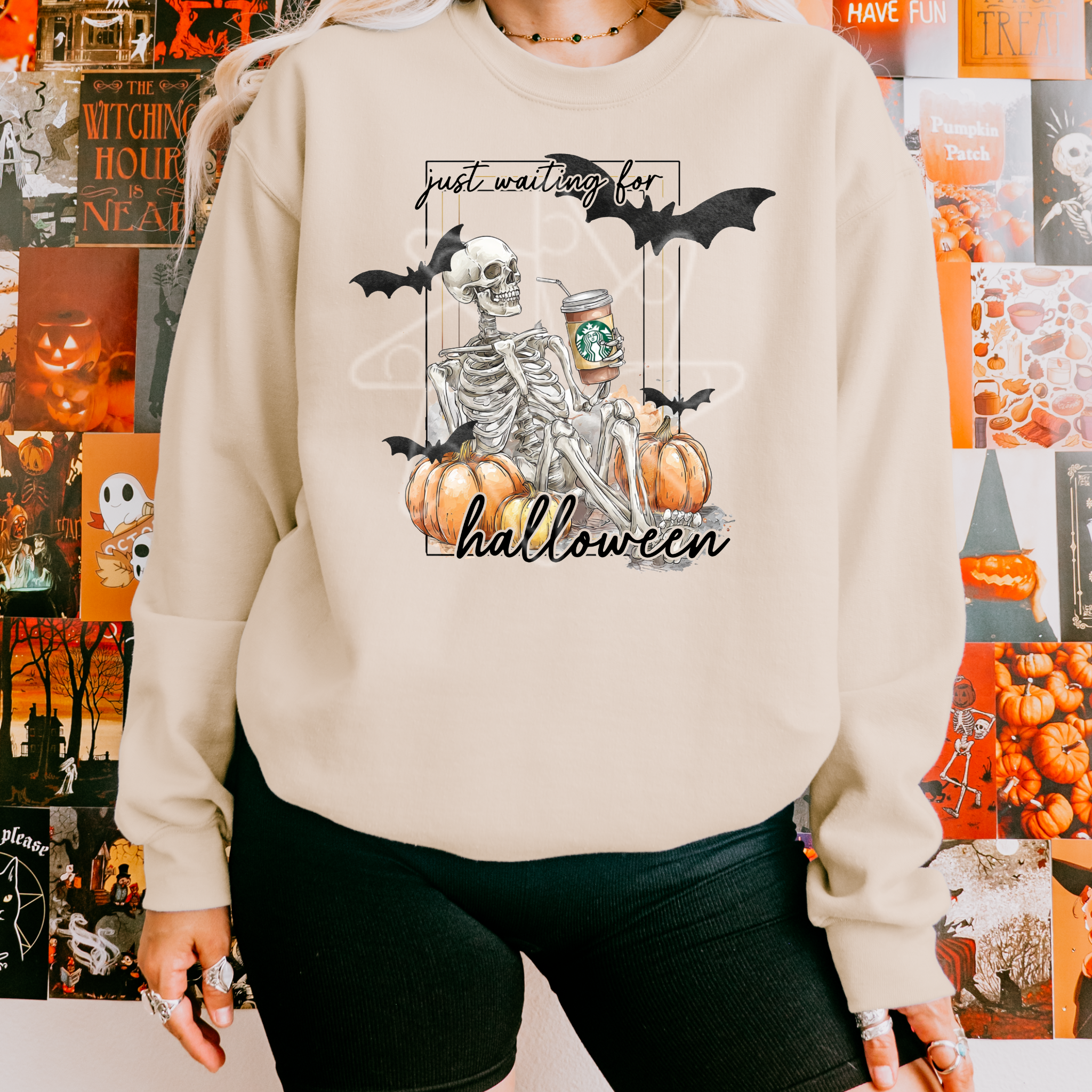 Person wearing a Halloween-themed sweatshirt with a skeleton and pumpkins design in front of a decorated wall.