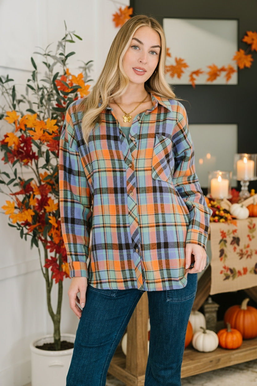 Woman wearing a plaid shirt and jeans standing indoors with a plant in the background