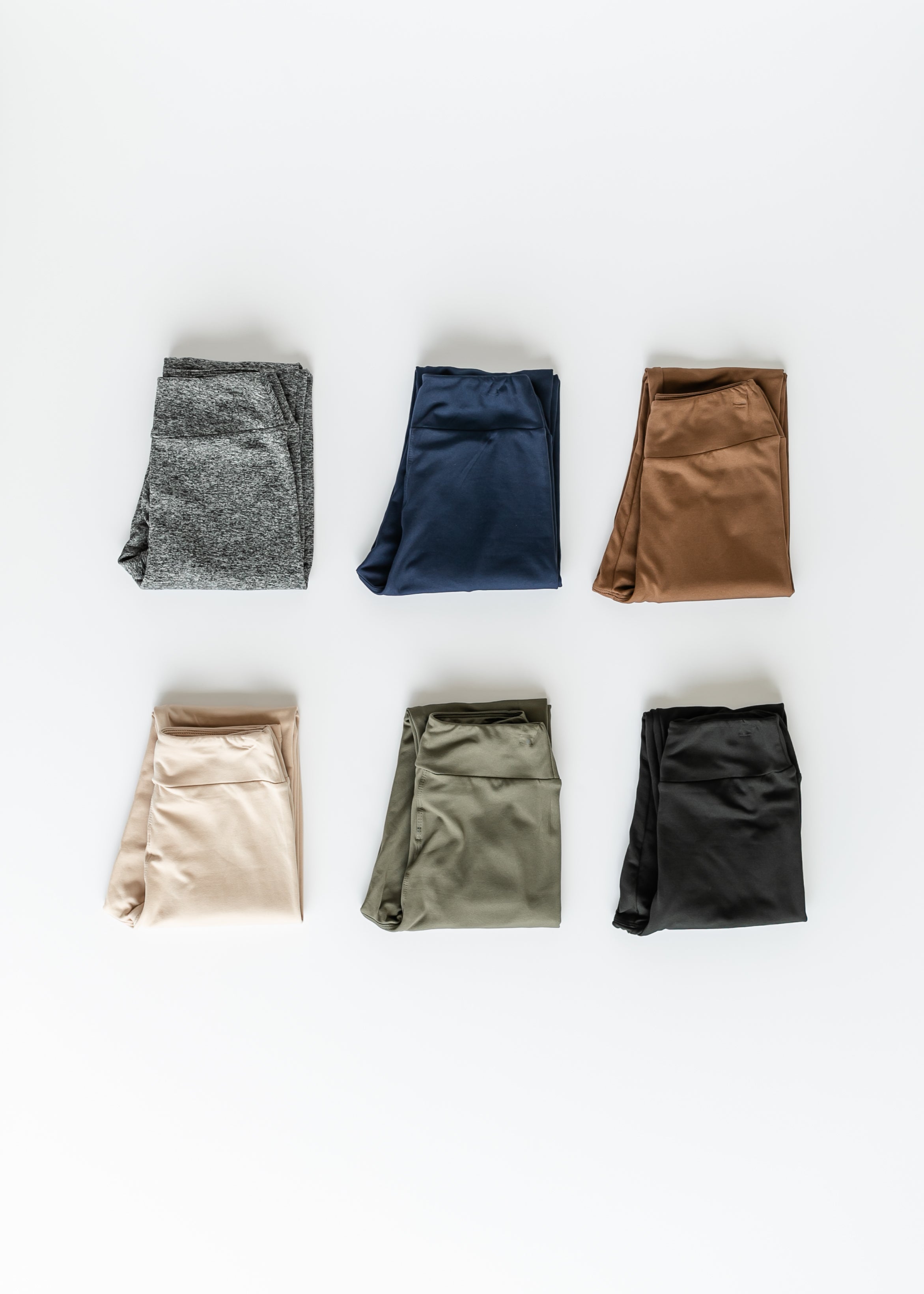 Six pairs of folded pants in different colors on a white background